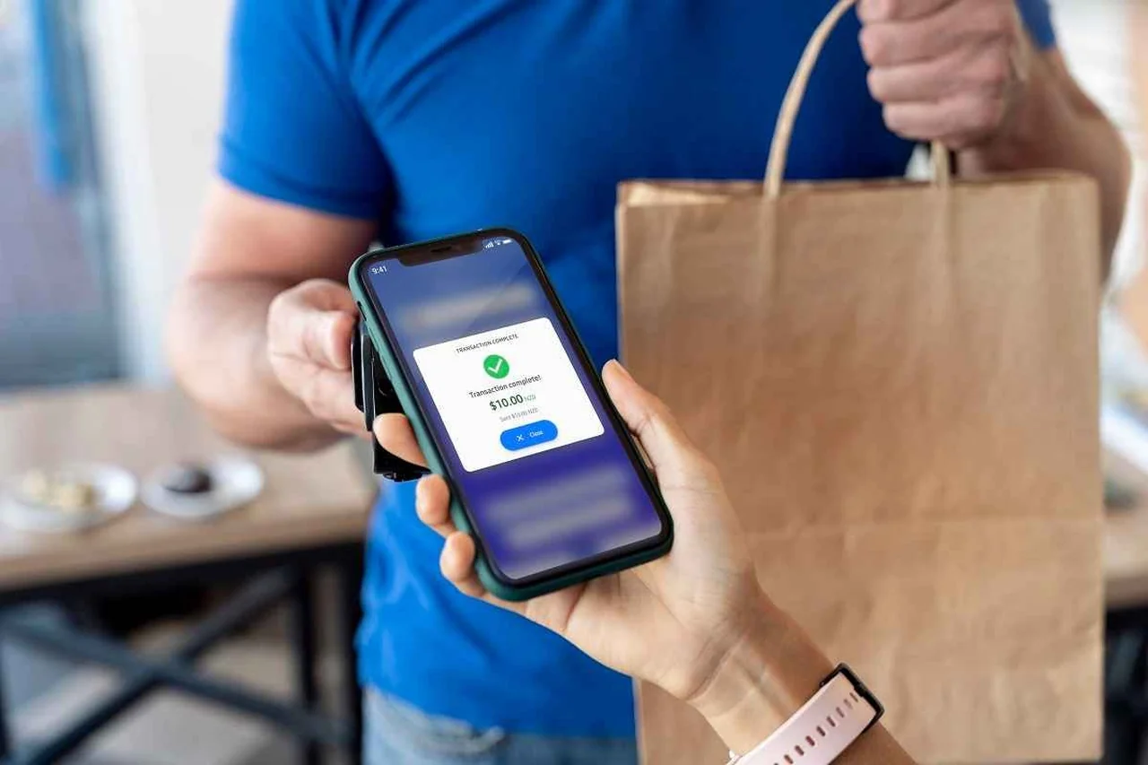 A customer paying with their phone at a counter